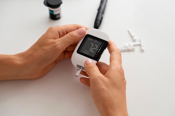 Close-up of hands holding a glucometer displaying a blood glucose reading, used for diabetes monitoring.